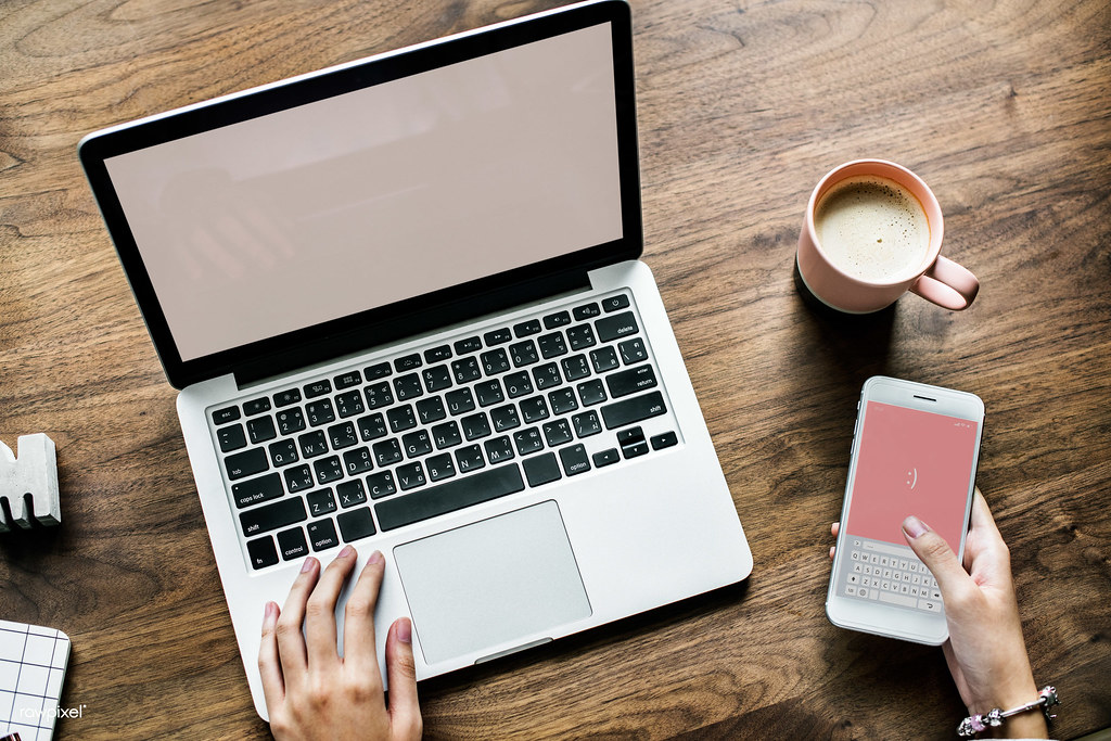 Aerial view of woman using computer laptop and a smartphone on wooden table (ecommerce laptop analytics)
